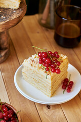 Cake on a wooden cake stand. Shortcrust pastry cake, decorated with red currants. Wooden background, side view.