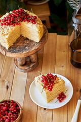 Cake on a wooden cake stand. Shortcrust pastry cake, decorated with red currants. Wooden background, side view.