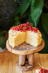 Cake on a wooden cake stand. Shortcrust pastry cake, decorated with red currants. Wooden background, side view.