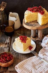 Cake on a wooden cake stand. Shortcrust pastry cake, decorated with red currants. Wooden background, side view.