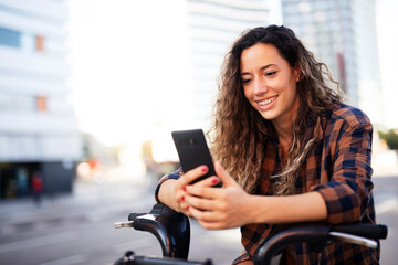Young lady on electric bicycle on the street. Beautiful girl using the phone