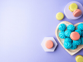 Heart shaped wooden dish with blue sweet meringues and macaroons
