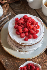 Vegan cake with raspberries, raspberry confit, coconut cream and almond biscuit. No flour. Side view, wooden background