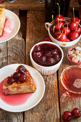 Cherry pie with jam in a bowl. Tea, flowers. Wooden background, side view