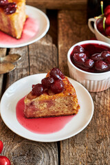Cherry pie with jam in a bowl. Tea, flowers. Wooden background, side view