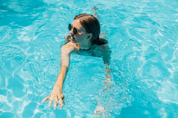 young woman in sunglasses relaxing in the water in the pool, Portrait of a happy woman in a swimsuit, floating water, relaxed woman in the pool