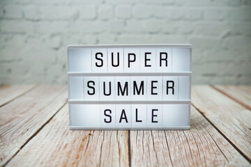 Super Summer Sale word in light box on wooden background