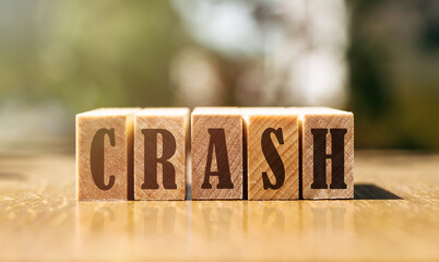 Word CRASH made with building wooden blocks on table in sunlight.