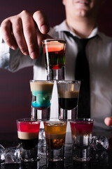 Barman preparing cocktail shots at the bar counter. Barman mixing drinks at the night club
