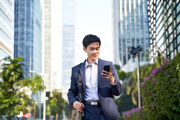 young asian business man looking at cellphone in the street