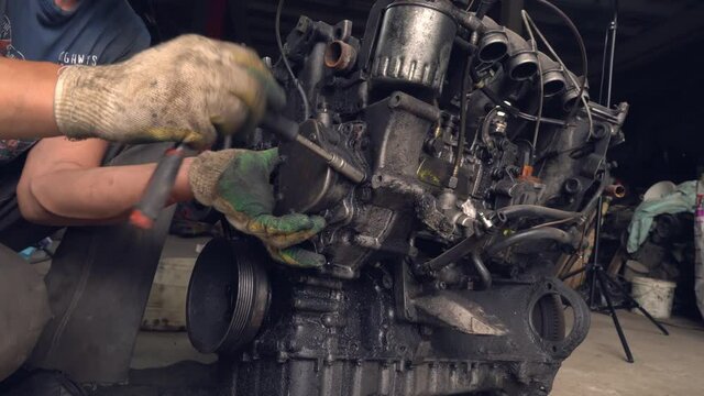 An auto mechanic checks the internal combustion engine. The engine is covered in oil and dirty. Its complete replacement also failed. Auto disassembly or car service .