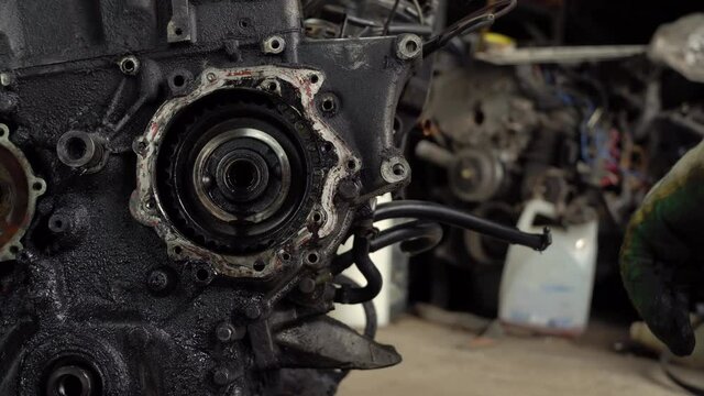 An auto mechanic checks the internal combustion engine. The engine is covered in oil and dirty. Its complete replacement also failed. Auto disassembly or car service .