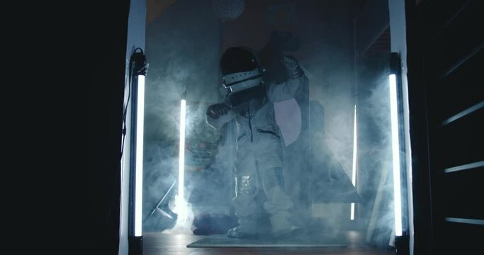 Future career aspirations. Happy fun child in astronaut suit dancing in dark room with lights, smoke at space ship.