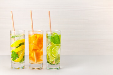Three glasses of citrus cocktails - lemon, orange, lime. Background - bleached wood 