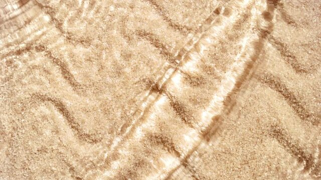 Multiple waves of water cross each other creating ripples spontaneously on brown sugar background | Background shot for organic scrub commercial