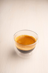 Coffee in glass cup on white wooden background
