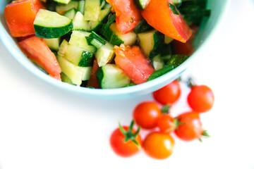 Vegetable salad in a plate on a white background. Chopped onions, tomatoes, cucumbers. Healthy food.