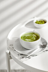 Green matcha tea with milk on cup with spoon on white table
