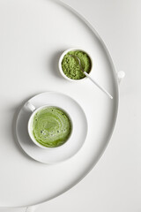 Green matcha tea with milk on cup with spoon on white table