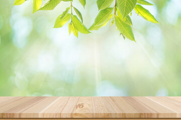 Wooden floor and green leaves with natural light bokeh background.