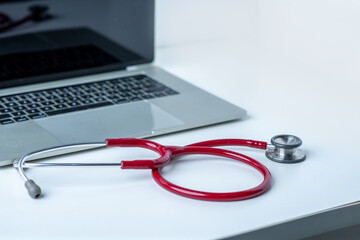 Stethoscope and computer on white desk in white background