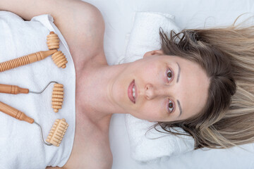 wooden massage tools spiked rollers, smooth roller lying on a white towel, top view. Woman having spa massage