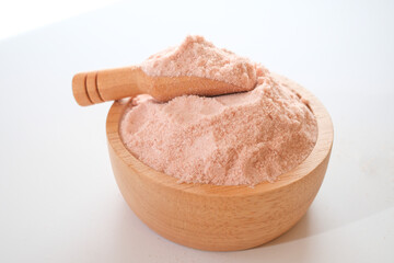 Himalayan pink salt powder in wooden bowl and scoop isolated on white background. 