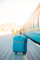 Fototapeta na wymiar Blue travel luggage on train station near railway on the city street. Adventure, discovery, transport and travel theme concept background.