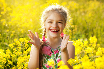 Happy little girl among yellow wildflowers