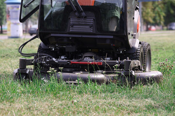 Tractor lawn mower mowing grass in park closeup