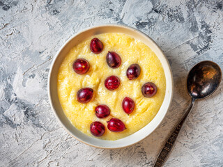 Corn porridge with gooseberries in a white plate for breakfast on a light background