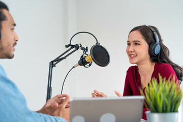 Asian Radio Host Podcast in Studio. Male and female speakers talk through mics and cameras on their...