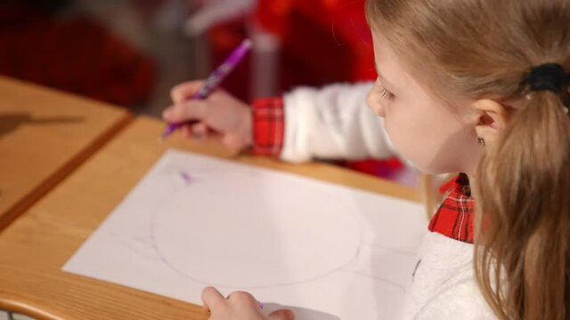Portrait of a lovely little girl indoors at Christmas. Cute child writing a letter to Santa. Beautiful small girl drawing a picture on xmas background at home