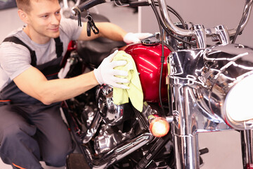 Man repairman wiping motorcycle tank with rag