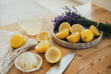 Fresh lemonade in the making: fresh lemons, lemon juice and juicer close up.