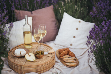 Beautiful picnic with wine, cheese, olives, ciabatta bread and croissants in a lavender field.