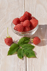 Red ripe raspberries. Homemade raspberry jam in a glass jar on a wooden white table, selective focus, a copy space