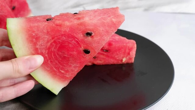 The girl takes a slice of watermelon from the plate. Berry. Fruits.