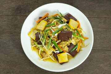 Stir Fried Bean Sprouts in white ceramic plate. Stir fried bean sprouts with yellow tofu, ground pork, carrots, pig's blood and shallot. Thai food.