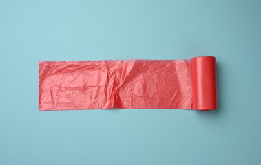 roll of red transparent plastic bags for trash can on blue background