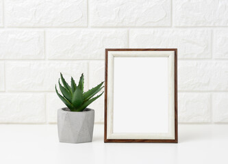empty white wooden photo frame and flowerpots with plants on white table