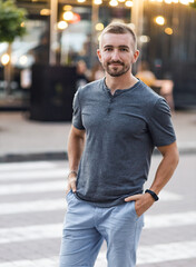 Fototapeta premium handsome guy in a gray T-shirt walks around the city. beautiful bokeh. gossip concept