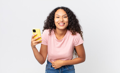 hispanic pretty woman laughing out loud at some hilarious joke and holding a smartphone