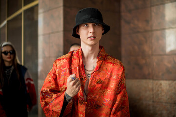 Positive man portrait with dressed in street style clothes red kimono with chains around neck....