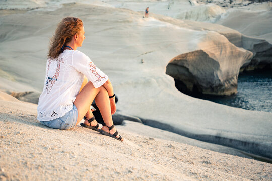 woman in white sitting on white rocks in Sarakiniko beach