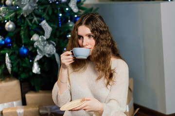 Beautiful young woman celebrating christmas at home, having fun while opening presents