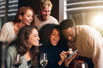 Friends looking at photos on phone in bar