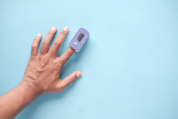 close up of man hand using pulse oximeter on blue background 