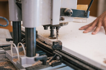 Industrial machine drilling a hole in a wooden panel in a workshop