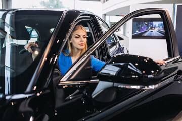 Woman sitting inside a car in a car showroom